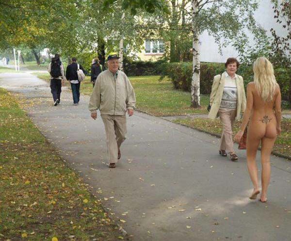 Нагая девушка гуляет в парке на людях