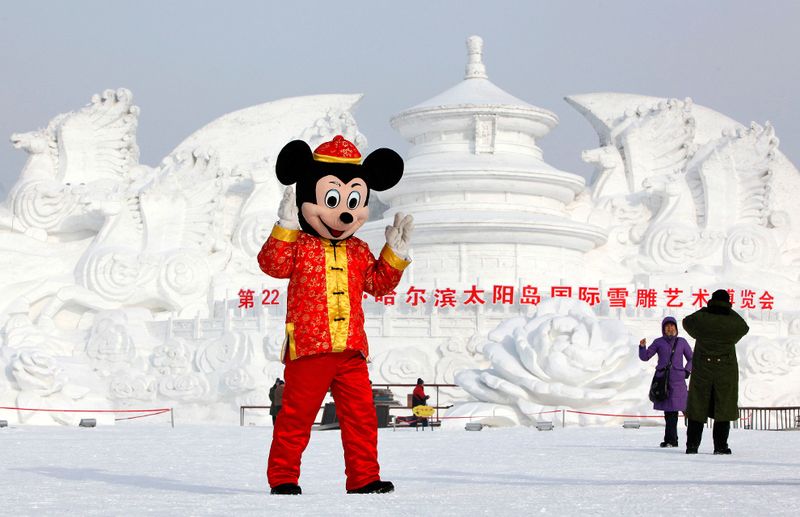 Человек в костюме Микки Мауса позирует перед скульптурой из снега в
 парке Харбина 5 января 2010 года. (REUTERS/Aly Song)