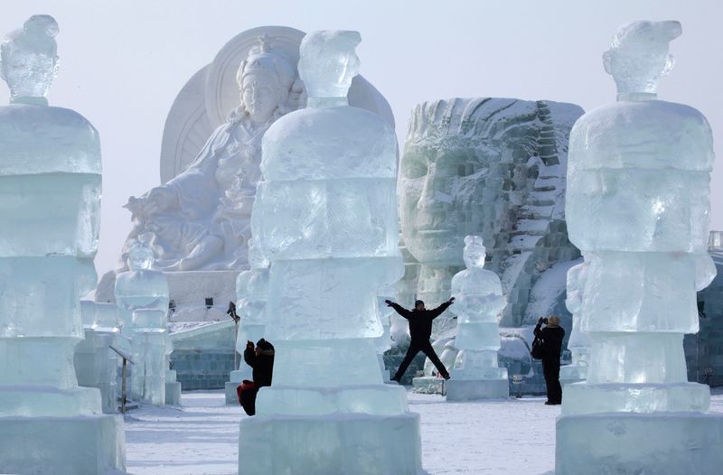 Посетители 26-ого Международного фестиваля снега и льда позируют 
рядом с гигантскими скульптурами в Харбине 5 января 2010 года. (AP 
Photo/Ng Han Guan)
