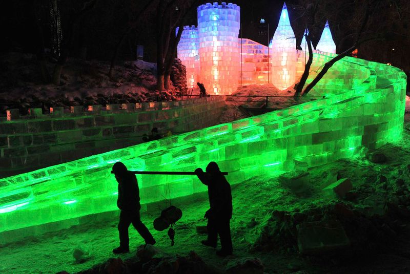 Рабочие проходят мимо ледяной скульптуры на фестивале в Харбине 18
 декабря 2009 года. (REUTERS/Sheng Li)
