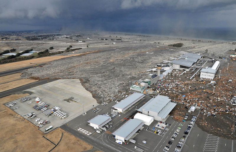 Вызванное землетрясением цунами несется к аэропорту Сендай в 
северной Японии 11 марта. (Kyodo News/Associated Press)