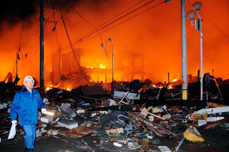 Спасатель среди обломков и горящих зданий после сильнейшего в истории Японии землетрясения. (Kyodo News/Associated Press)