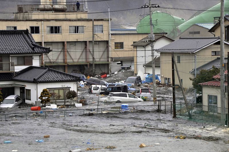 Волны обрушились на дома и автомобили в городке Кесеннума в 
префектуре Мияги. (AFP/Getty Images)