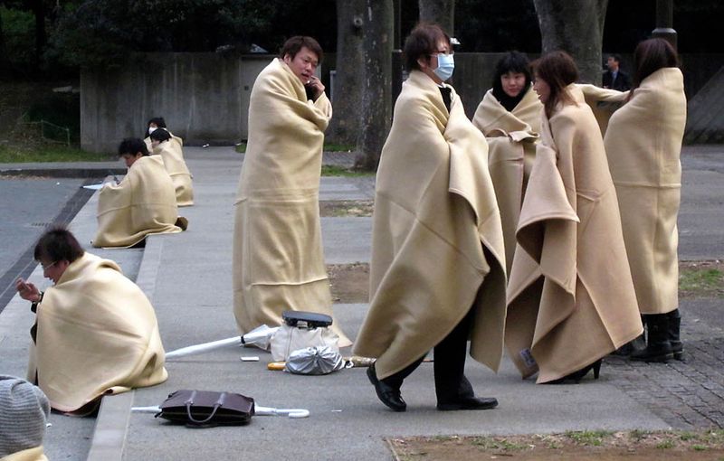 Укрывающиеся в одеяла прохожие в парке в Йокохаме после сильного 
землетрясения. (Shuji Kajiyama/Associated Press)