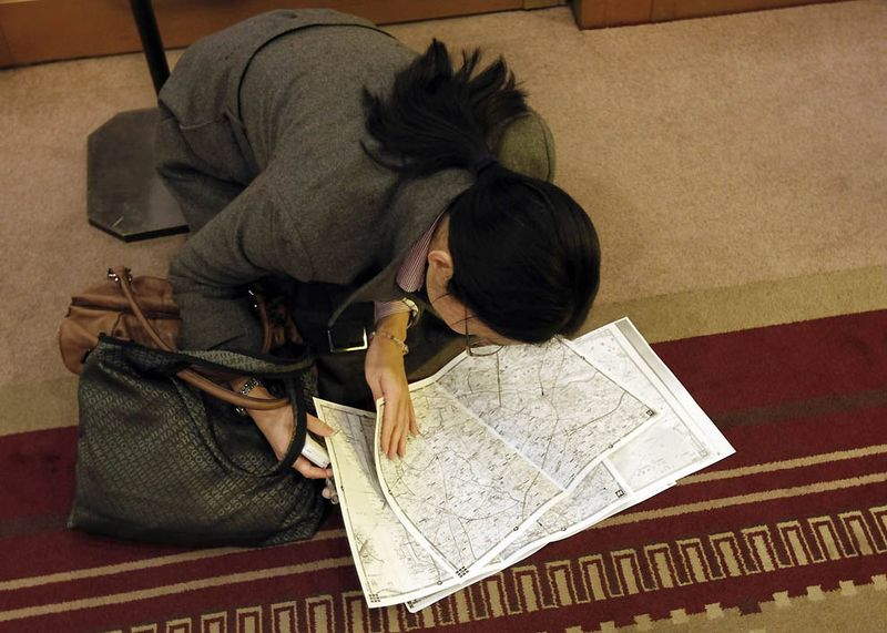 Сверяющая карты девушка пытается найти маршрут в вестибюле отеля, после того как в Токио приостановили движение метро и поездов. (Kim Kyung-Hoon/Reuters)