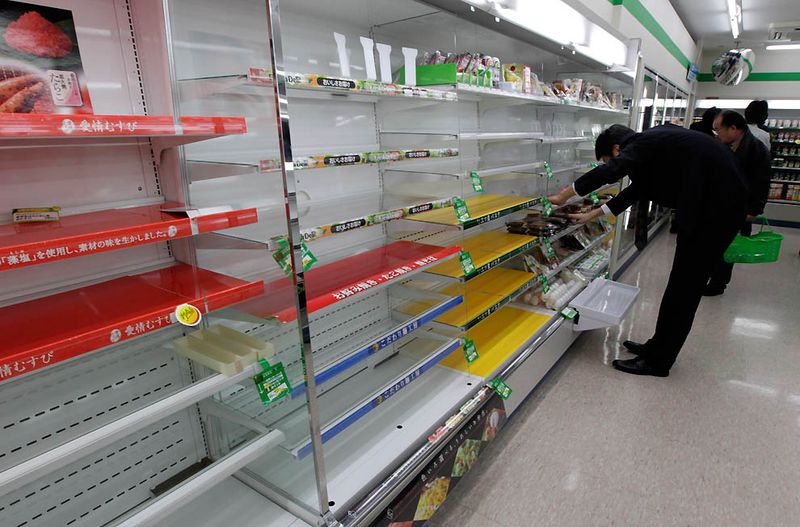 Покупатель ищет продукты почти пустых полках одного из токийских 
магазинов, после того как люди раскупили все, так как не могут вернуться
 домой после землетрясения. (Yuriko Nakao/Reuters)