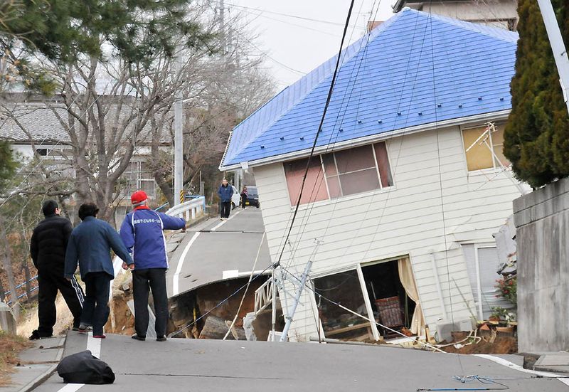 Жители оценивают ущерб на дороге в Сукагаве, префектура Фукусима. 
(Fukushima Minpo/AFP/Getty Images)