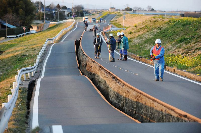 Рабочие осматривают обвалившийся участок дороги в Сатте, префектура
 Саитама, после землетрясения. (Saitama Shimbun/Associated Press/Kyodo 
News)