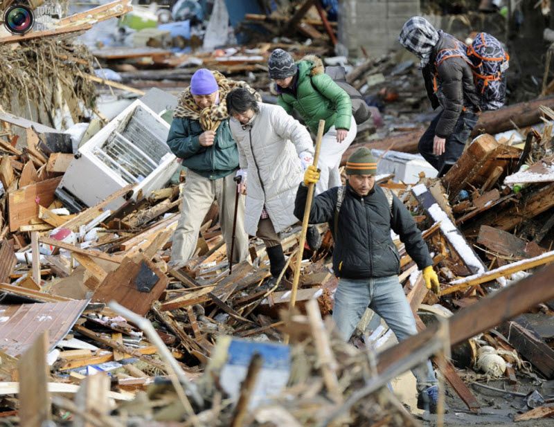 Люди среди развалин жилых домов в Сендай, 12 марта 2011 года.