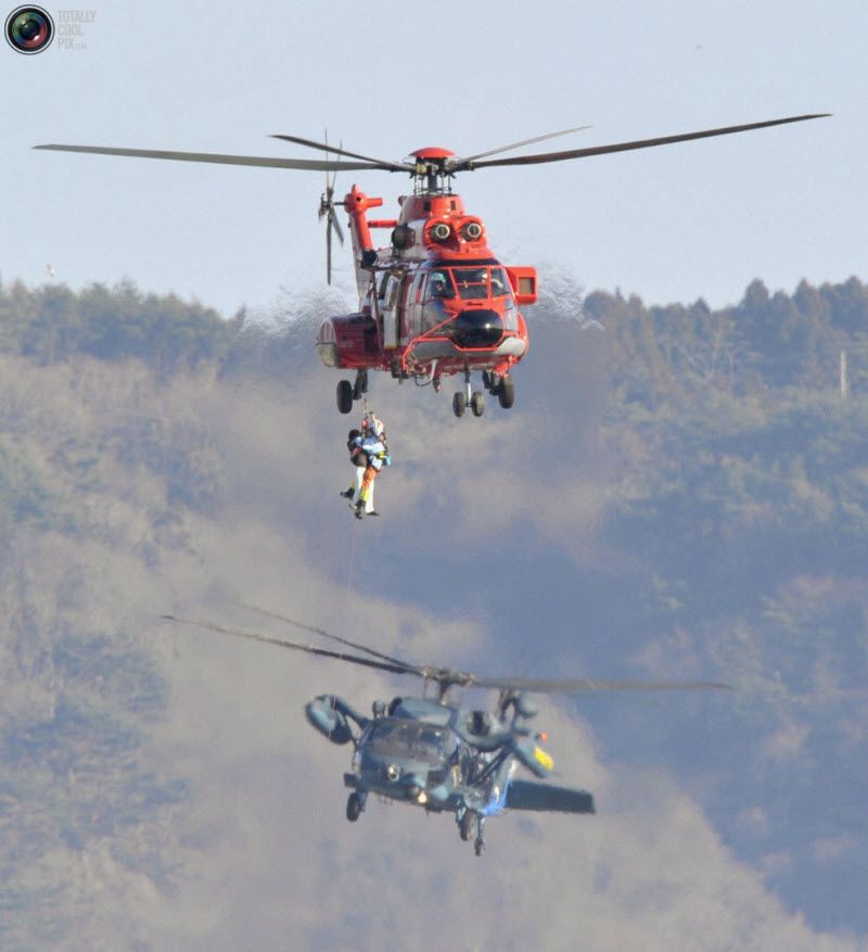 Оказавшегося запертым в здании японца спасает вертолет, город 
Кесеннума, префектура Мияги, 12 марта 2011 года.