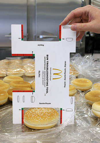 На снимке: специальный картонный прибор, позволяющий оценить правильность габаритов и ровность нарезки булочек для гамбургеров/чизбургеров (верхний вырез), 