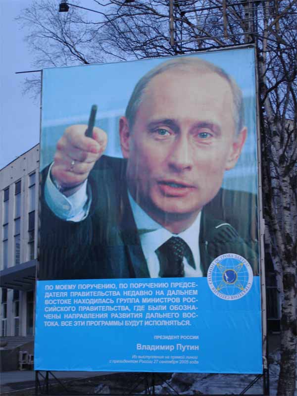 Над городом возвышается мужчина, указующий ручкой. Складывается впечатление, что именно он виноват во всем происходящем. Наверное для этого впечатления его сюда и повесили.