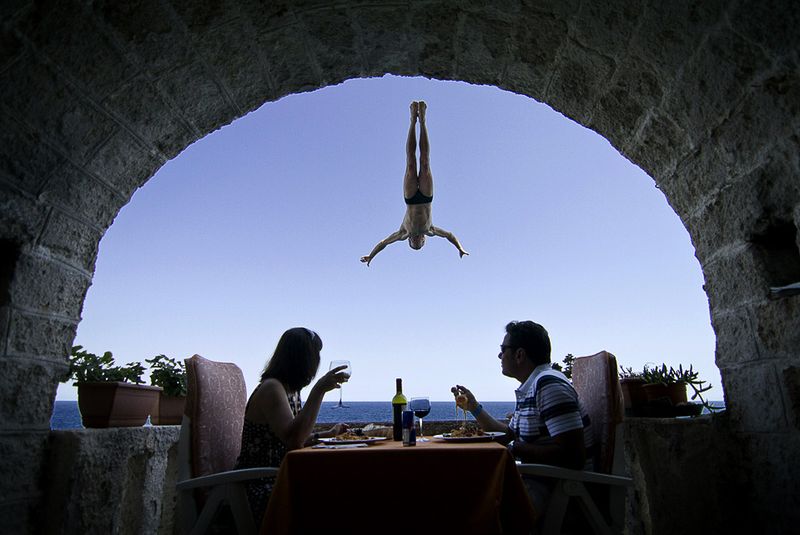Итальянская пара, чья компания продает мебель с доставкой, во время ланча с балкона наблюдает за тем, как Стив Блэк совершает свой прыжок со скалы на соревнованиях по клифдайвингу 5 августа, Италия. (DEAN TREML/AFP/Getty Images)