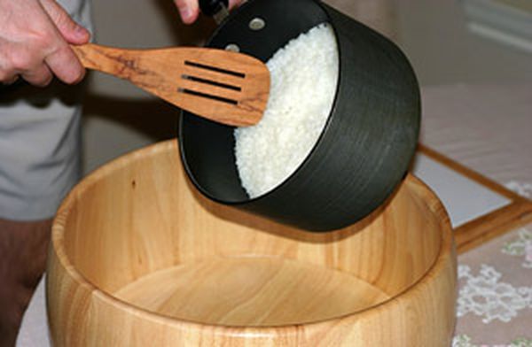 3. Варка риса. Поместить промытый рис в глубокую кастрюлю. На каждую чашку риса добавить 250 мл холодной воды (в нашем случае 500 мл). Закрыть крышкой, поставить максимальный нагрев и быстро довести до кипения (займет около 5-7 минут). Затем, выставить нагрев на минимальное значение и оставить на 12 минут. По истечении этого времени вода полностью впитается в рис, и на его поверхности появятся небольшие вентиляционные отверстия. Не снимая крышки, убрать кастрюлю с огня, и дать настояться еще 15 минут.