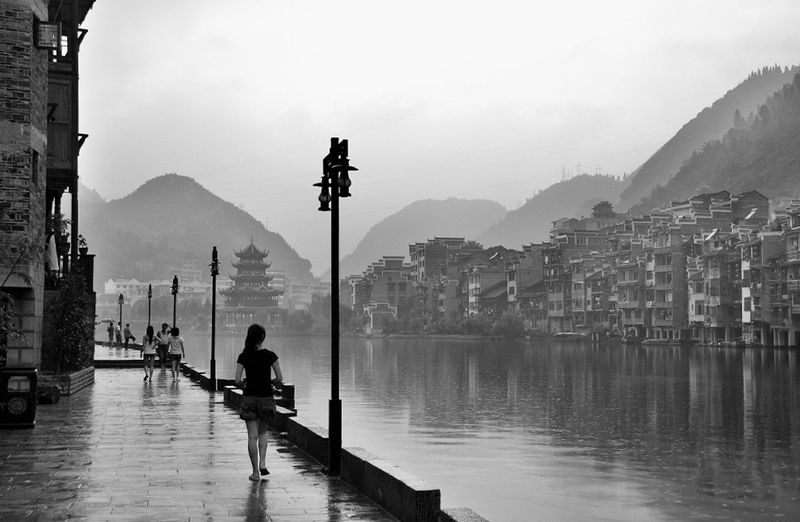Прогулка вдоль реки. Это фото было сделано этим летом в китайском городе Чженьян. Я прогуливался вдоль реки в тумане после вечернего дождя. Освежающий запах после дождя смешивался с ароматом стоявших неподалеку лотков с едой. Вдалеке смеялись и играли дети. Умиротворенная жизнь местных людей напомнила мне о том радостном времени, когда я сам рос в подобном городке на юго-западе Китая. (Photo and caption by Fred Wang)