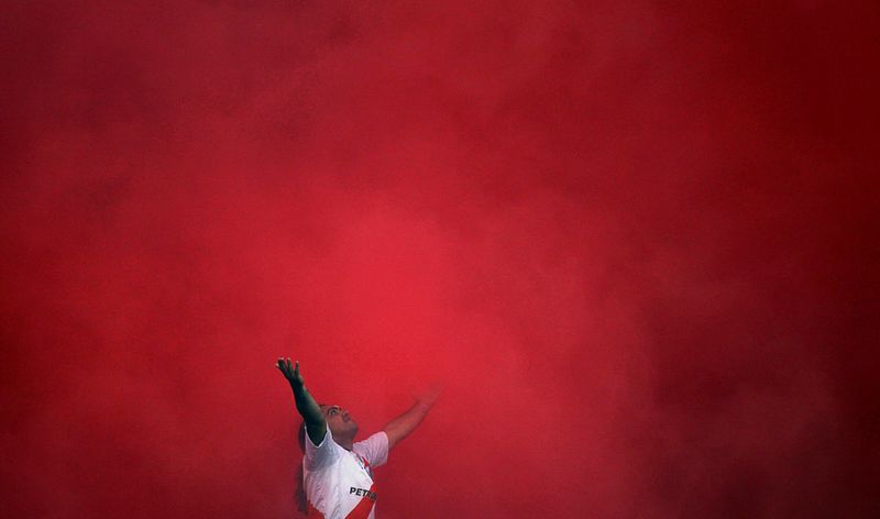 Фанат команды «River Plate» в смоге от дымовых шашек перед началом матча Аргентинского Первого Дивизиона между его любимой командой и «Boca Juniors», 16 ноября, Буэнос-Айрес. (REUTERS/Marcos Brindicci)
