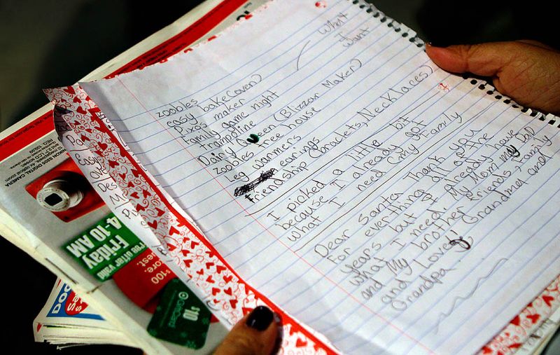 Покупательница сверяется со списком, который ее ребенок написал Санта-Клаусу. Снимок сделан в универмаге игрушек "Toys R Us" в городе Торренс, штат Калифорния. (Liz O. Baylen / Los Angeles Times)