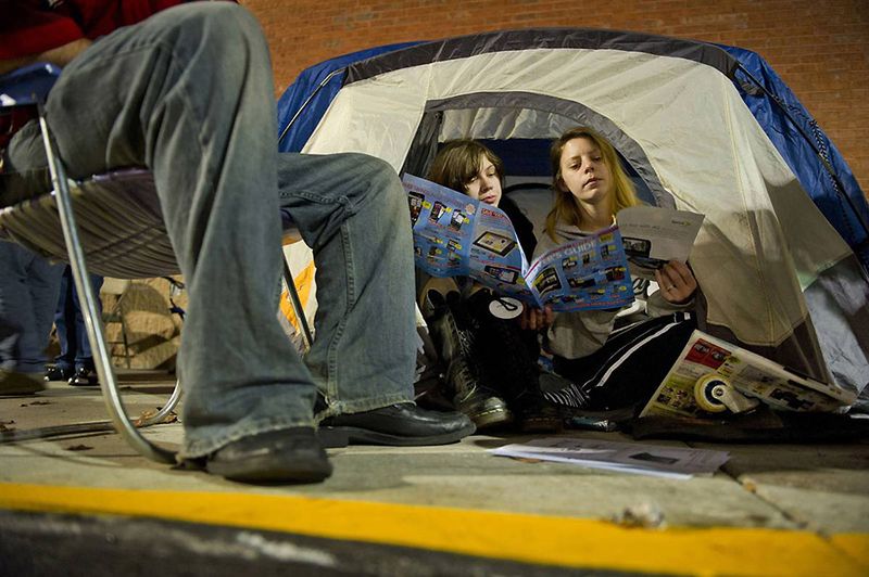 Никки Дональд (слева) и Барби Харрис рассматривают рекламные буклеты в палатке в ожидании открытия универмага Best Buy в 5 утра в Атланте. Они, как и сотни других людей, заняли очередь еще ночью. (Rich Addicks / AP)