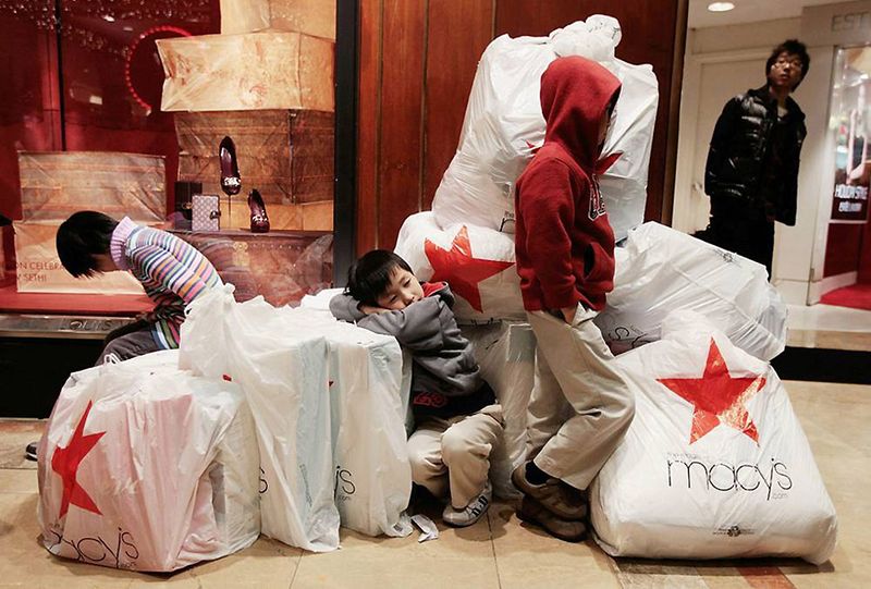 Дети в ожидании своих родителей рядом с купой пакетов в покупками в универмаге Macy's. В прошлом году напуганные рецессией крупнейшие торговые сети обрушили цены к рождественскому сезону на 50% и более по отношению к рекомендуем производителями. В этом году скидки были гораздо меньше. (Chris Hondros / Getty Images)