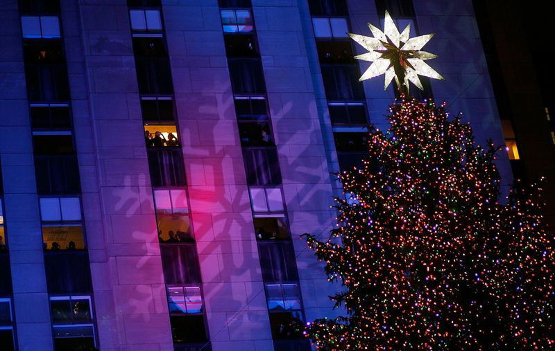Люди смотрят на елку из Рокфеллеровского центра  после ежегодной церемонии зажжения рождественских огней в Нью-Йорке 30 ноября. Тысячи людей пришли посмотреть на зажжение 12-тонной 22-метровой норвежской елки во время одной из главных церемоний Нью-Йорка.