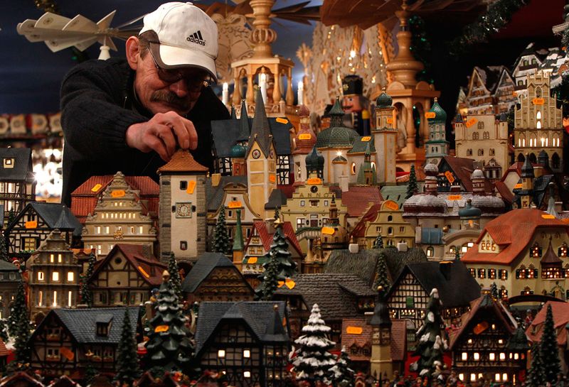 Мужчина ставит модели домиков на старейшем рынке Германии Кристкиндлсмаркт в Нюрнберге 26 ноября.