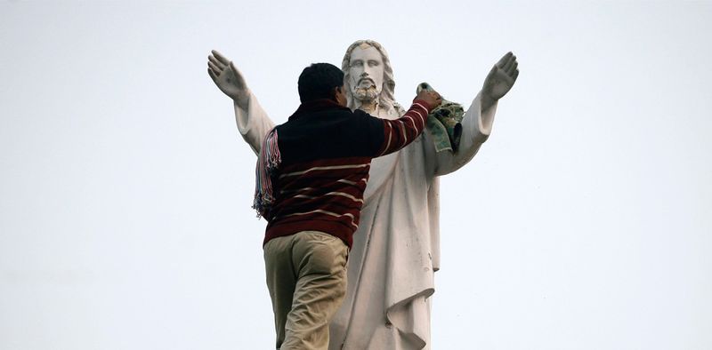 6. Мужчина чистит статую Иисуса Христа на крыше церкви в городе Нойда, расположенном в северном индийском штате Уттар Прадеш. (REUTERS/Parivartan Sharma)