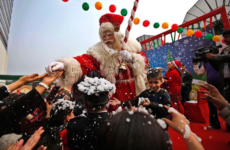 16. Санта Клаус раздает конфеты детям у отеля «Le Meridien» в Нью-Дели 25 декабря. Христиане в Индии составляют чуть больше 2% из миллиардного населения. (AP Photo/Mustafa Quraishi)