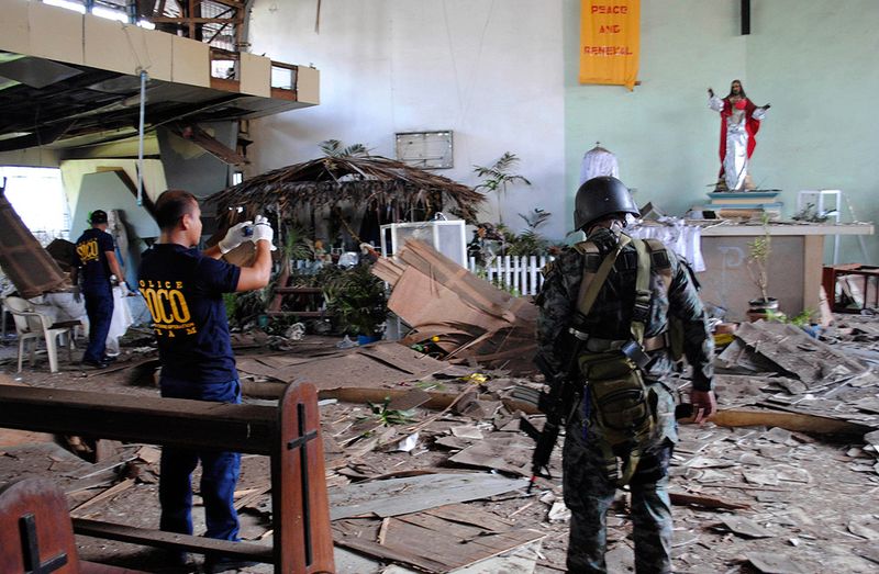 24. Следователи филиппинской национальной полиции оценивают ущерб, нанесенный католической часовне после взрыва во время рождественской службы на неспокойном острове Джоло, провинция Сулу, 25 декабря. Бомба взорвалась во время службы в полицейском лагере, в результате чего был ранен священник и 10 прихожан. Бомба была спрятана в вентиляционном отверстии у потолка часовни, расположенной на территории полицейского лагеря на острове Джоло, где активно промышляют боевики, связанные с аль-Каидой. (AP Photo/Nickee Butlangan)