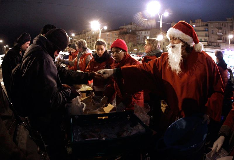 29. Мужчина в костюме Санта-Клауса раздает подарки бездомным во время праздничного ужина перед службой в автобусе в Ницце. (REUTERS/Eric Gaillard)
