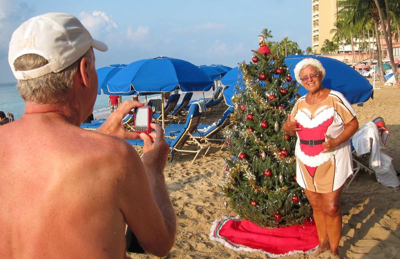 32. Туристка в костюме миссис Клаус позирует для фото у елки на пляже Ваикики в Гонолулу, Гавайи. (REUTERS/Kevin Lamarque)